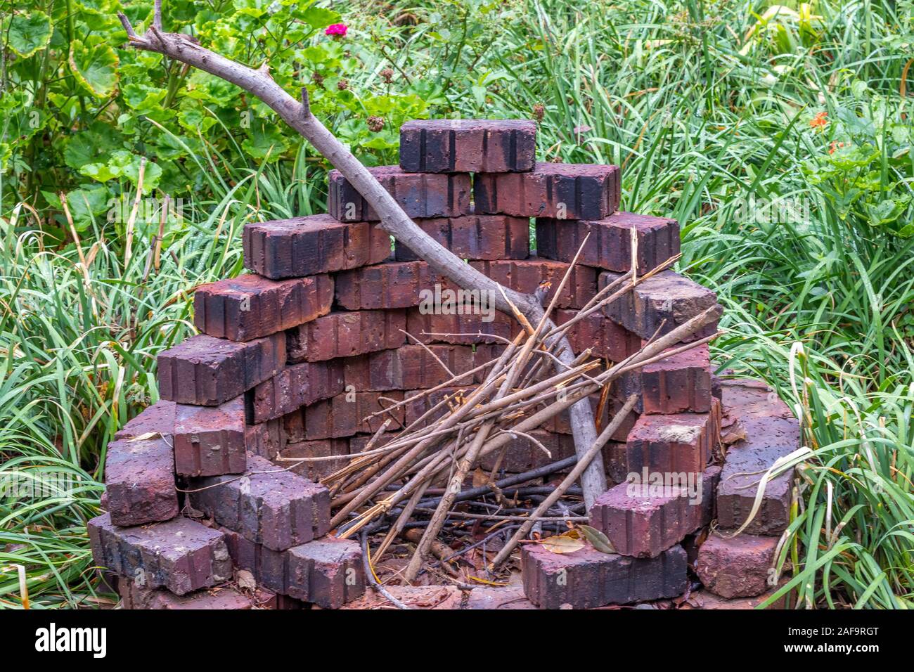 Eine kreisförmige Feuerstelle aus losen Ziegel gebaut gegen einen grünen  Garten Hintergrund Bild im Querformat isoliert Stockfotografie - Alamy