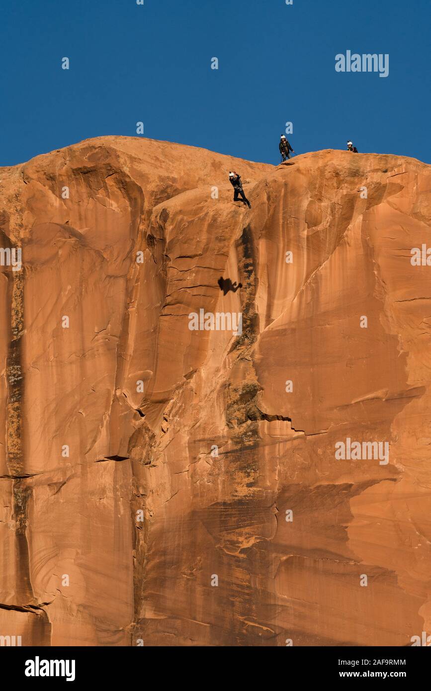 Ein BASE jumper Sprünge von der Spitze des 400-Fuß vertikale Teilfläche der Tombstone in der Kane Springs Canyon in der Nähe von Moab, Utah. Hinweis seinen Schatten auf die Klippe. Stockfoto