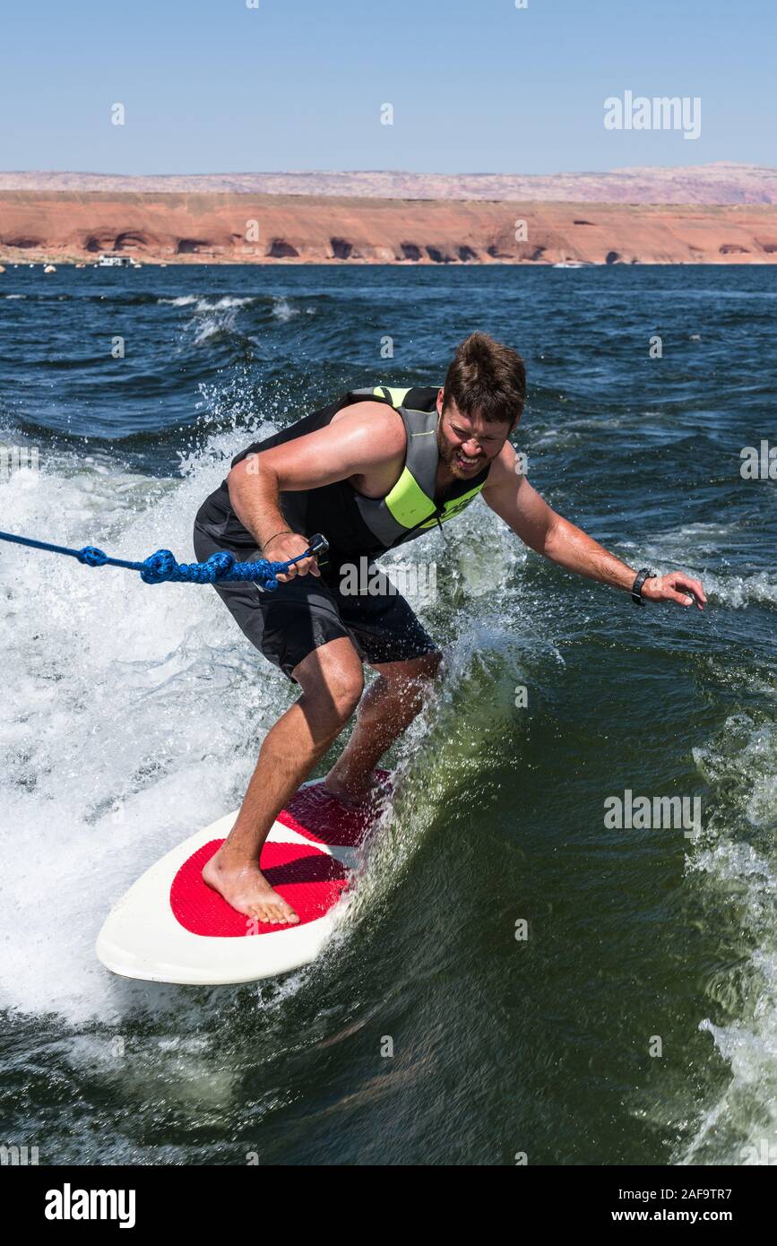 Ein junger Mann wake Surfen hinter einem Boot auf dem Lake Powell in der Glen Canyon National Recreation Area im südlichen Utah, USA. Stockfoto