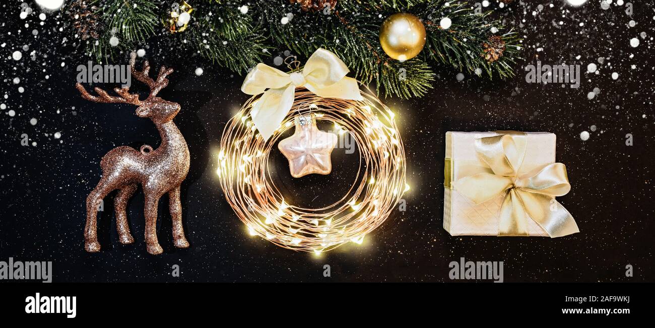 Weihnachten und neues Jahr Dekorationen auf dunklem Hintergrund: Weihnachtsbaum, Gold Dekorationen, Rentier, Garland, Geschenk Stockfoto