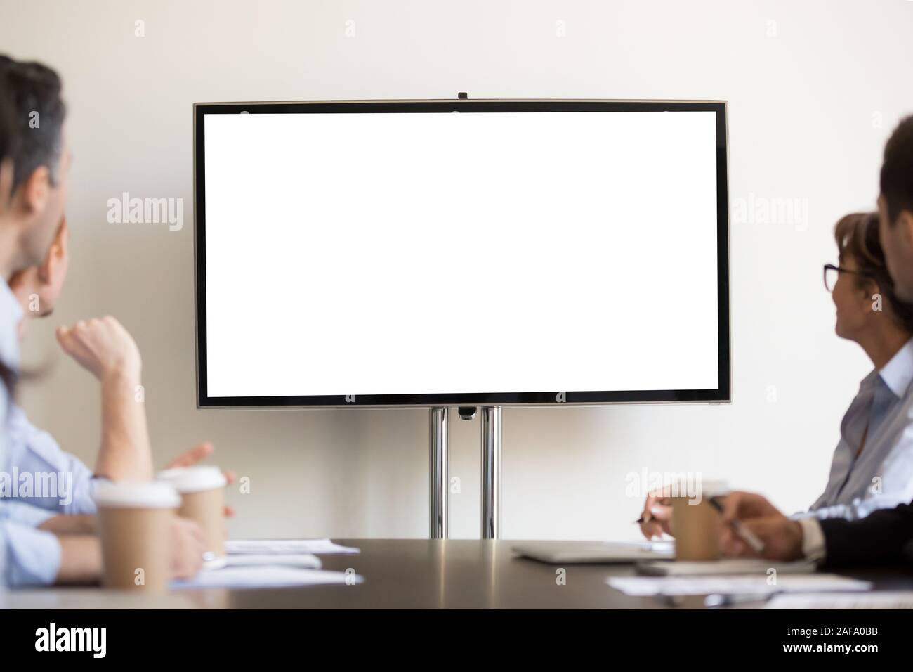 Geschäftsleute, die Sitzung im Sitzungssaal auf tv mit weißen leeren Stockfoto
