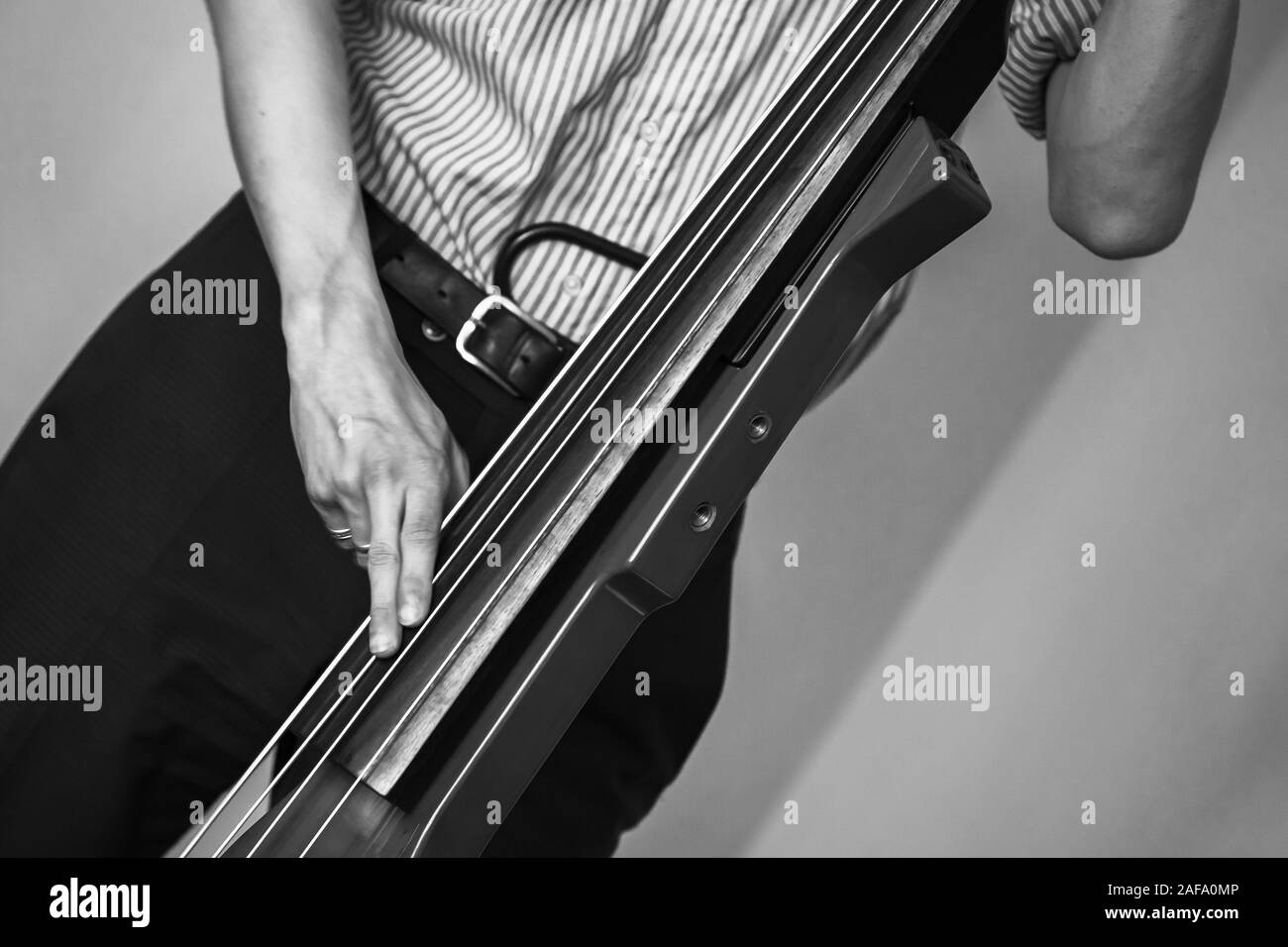 Mann spielt Rot moderne elektrische Kontrabass in der musikalischen Studio. Retro stilisierten Schwarzweiß-Foto Stockfoto