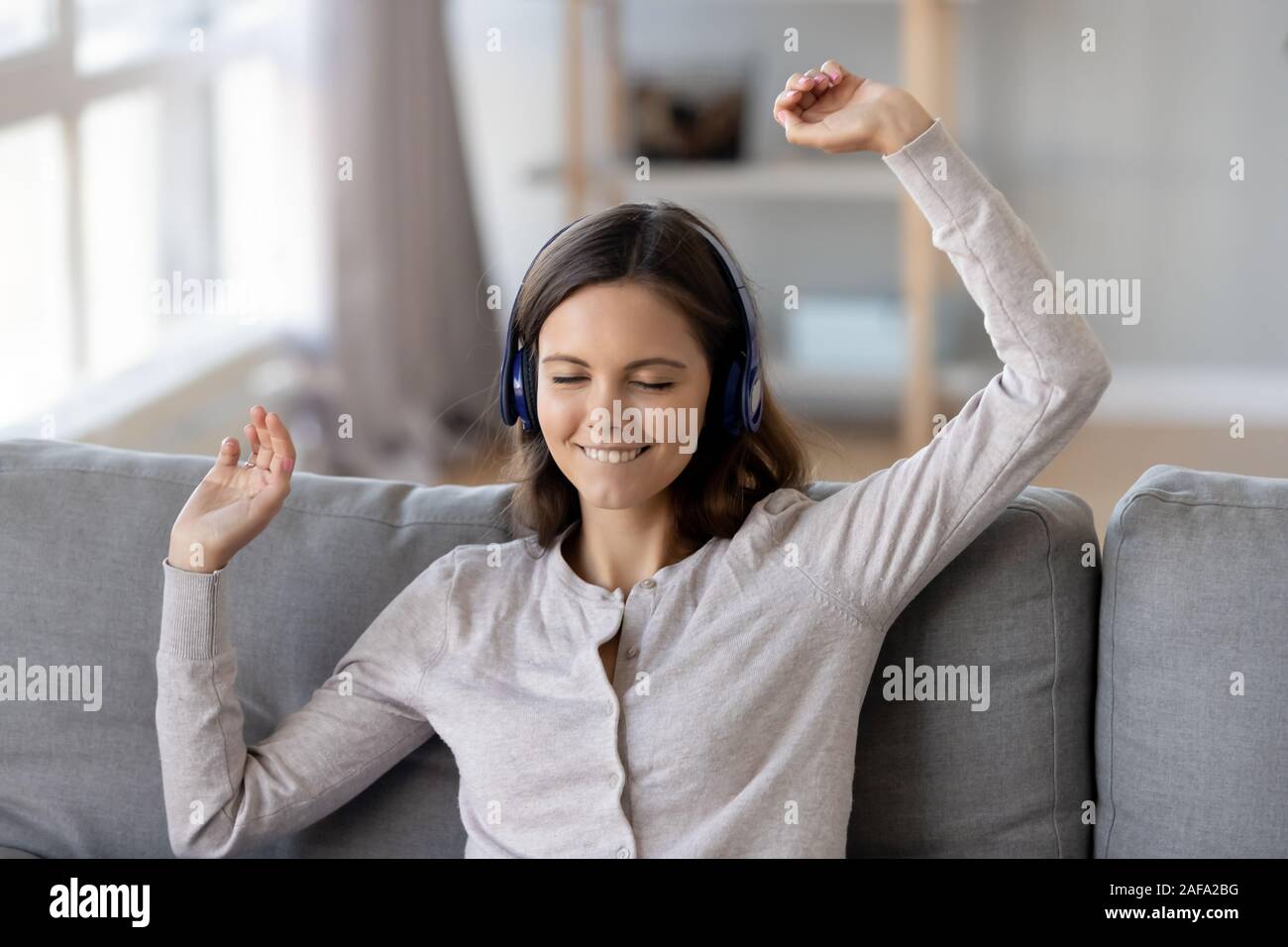Lächelnde Mädchen in die drahtlosen Kopfhörer genießen Sie Musik Stockfoto
