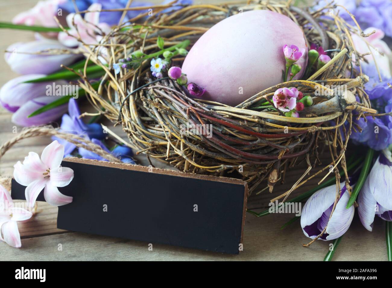 Osternest mit einem violetten Ei und einem unbeschriebenen Blatt auf einer hölzernen Hintergrund Stockfoto