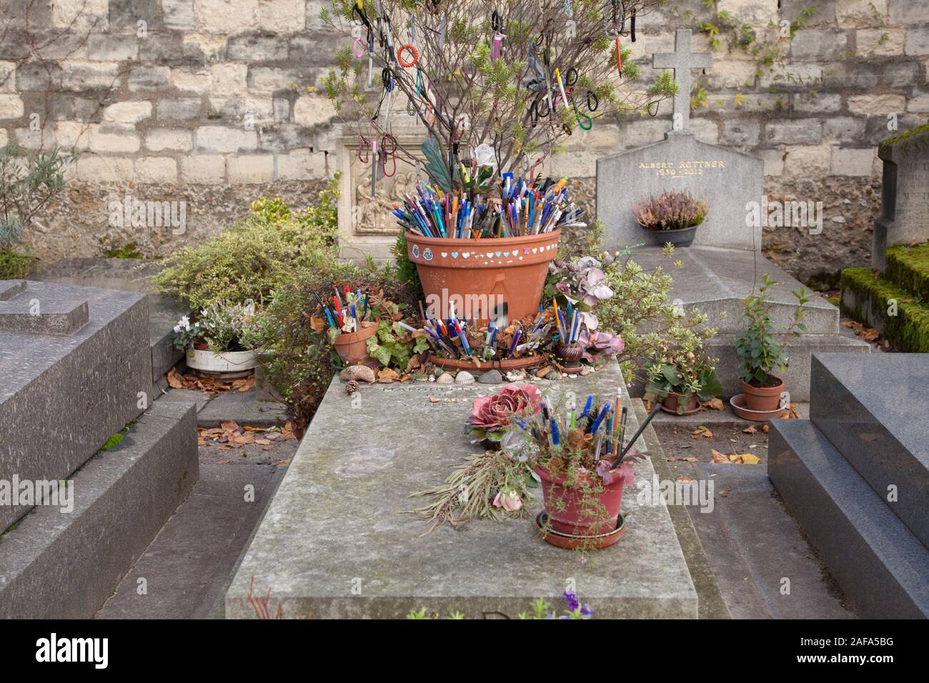 Das Grab der französische Romancier und Dramatiker Marguerite Duras in Friedhof Montparnasse ist mit Stiften und Token durch Besucher und Fans links abgedeckt Stockfoto