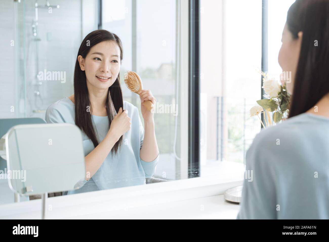 Asiatische Frau Kämmen vor Spiegel Stockfoto