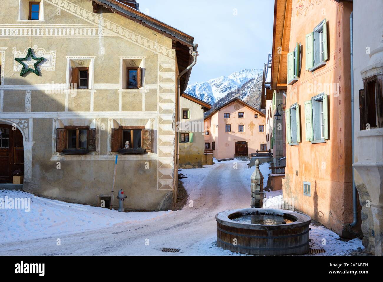 Gewundenen Straße mit typischen Häuser und Brunnen im älteren Teil von Guarda, Inn Bezirk, Kanton Graubünden, Schweiz. Stockfoto