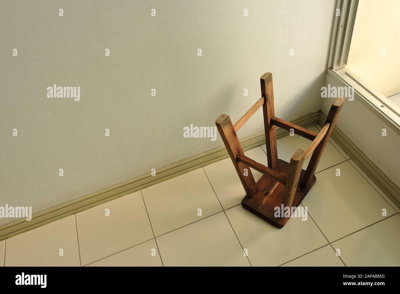 Hohe Betrachtungswinkel von Vintage Teakholz Stuhl auf den Kopf gestellt auf ebenem Boden, die Illusion macht es scheinen Ebene geneigt sein Stockfoto