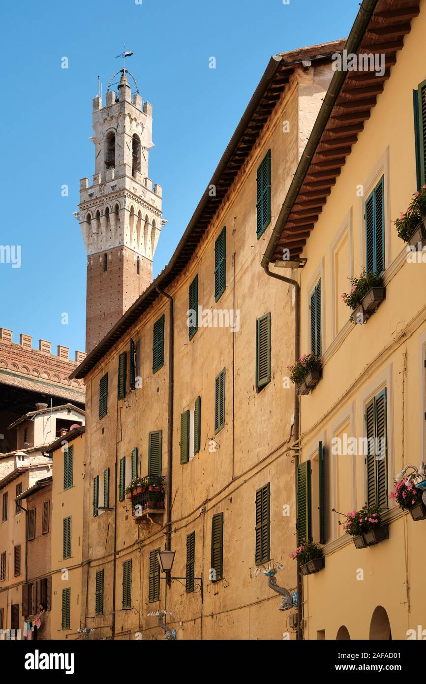 Der Torre del Mangia und bemalten Häuser und die Straße in das UNESCO-Weltkulturerbe von Siena, Toskana, Italien EU Stockfoto