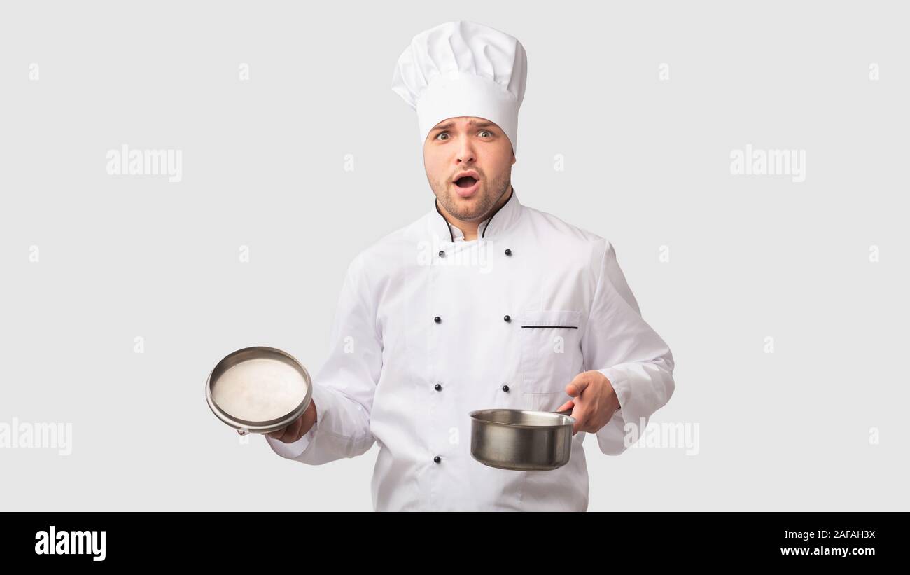 Verwirrt Cook Mann Öffnung Topf stehen auf weißen Studio Hintergrund Stockfoto