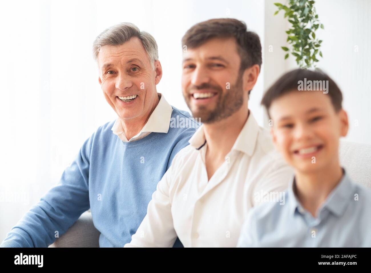 Älterer Mann mit Middle-Aged Sohn und Enkel Sitzen auf der Couch Stockfoto