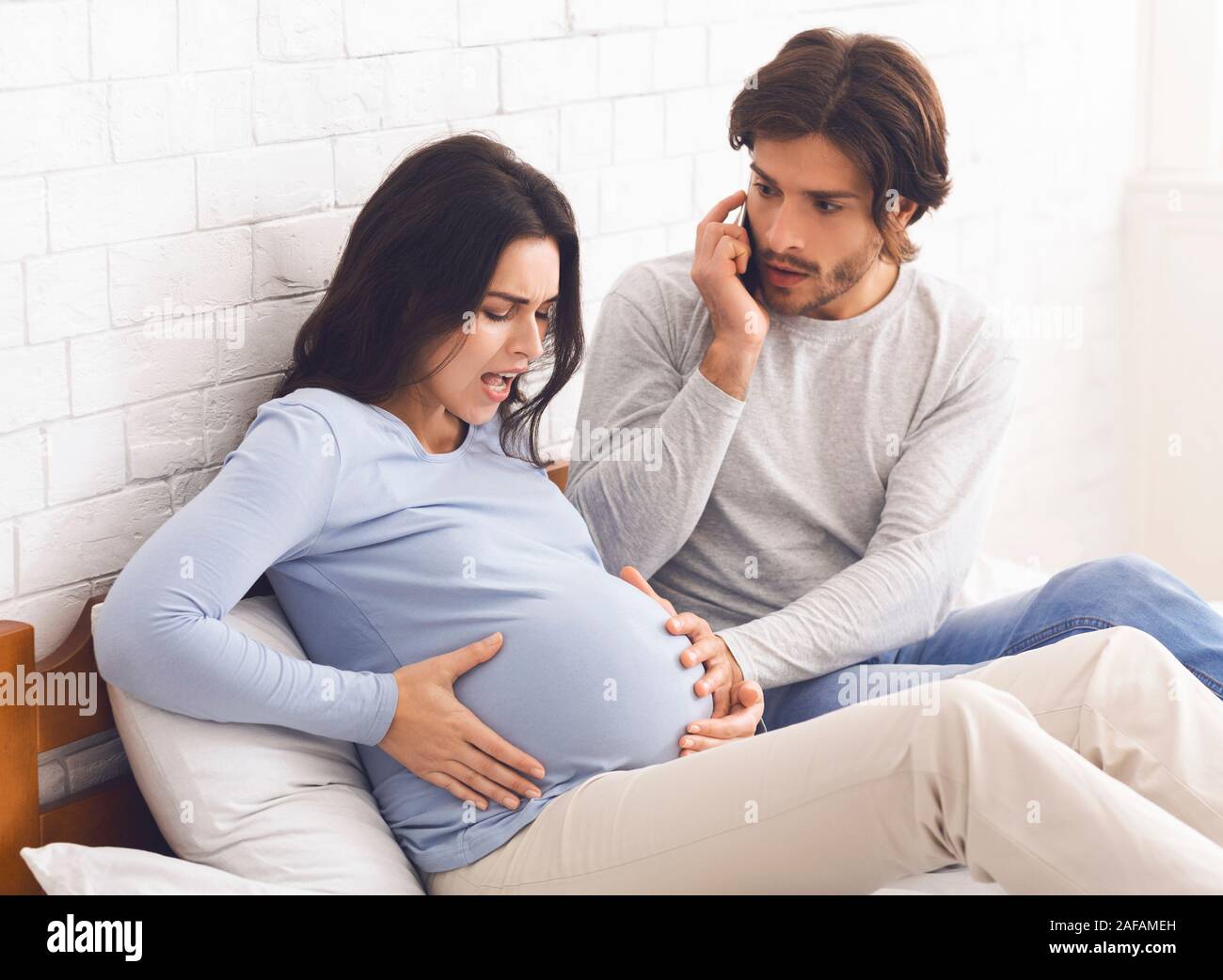 Schwangere Frau in Wehen, ihre Panik Ehemann Berufung Arzt Stockfoto