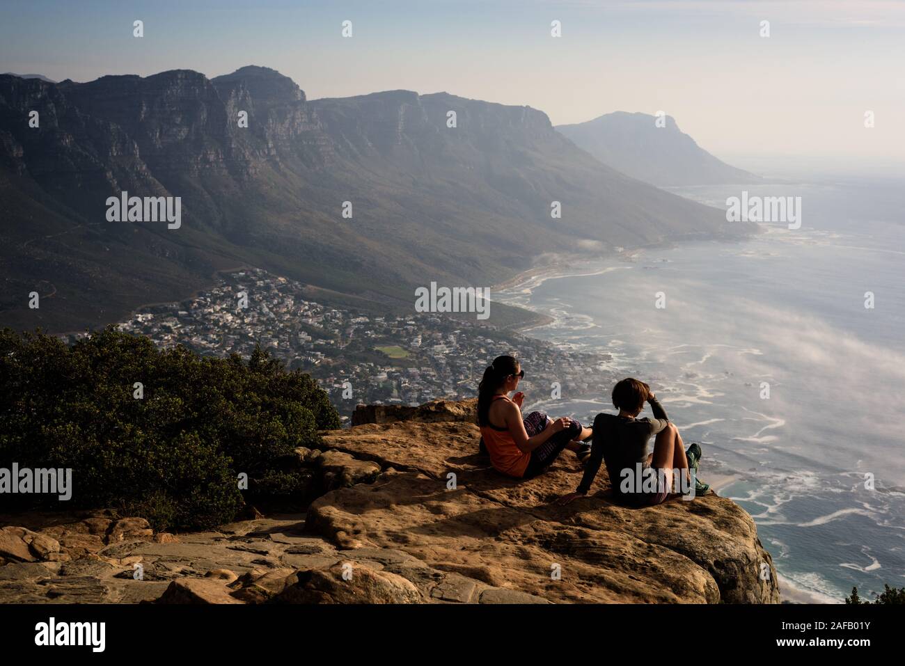 Freunde thront auf dem Gipfel von Kapstadts Lion's Head Mountain Blick über das Camp Bay Strände in Richtung Cape Point. Stockfoto