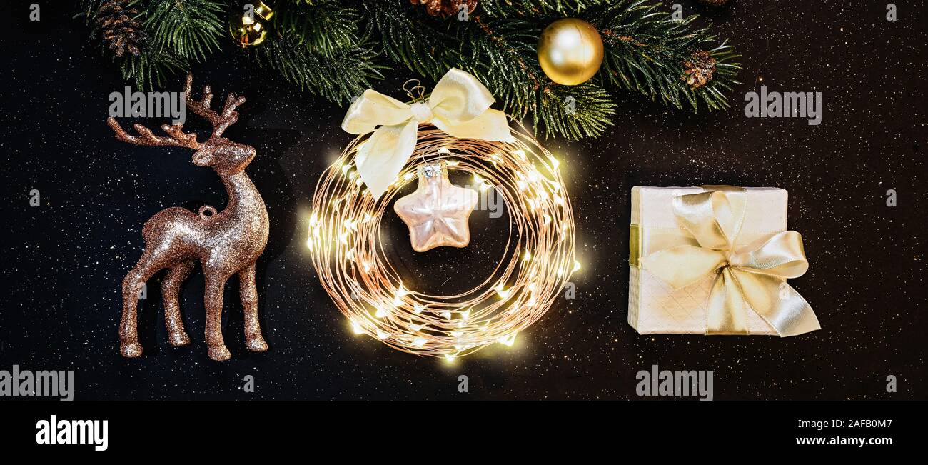 Weihnachten und neues Jahr Dekorationen auf dunklem Hintergrund: Weihnachtsbaum, Gold Dekorationen, Rentier, Garland, Geschenk Stockfoto