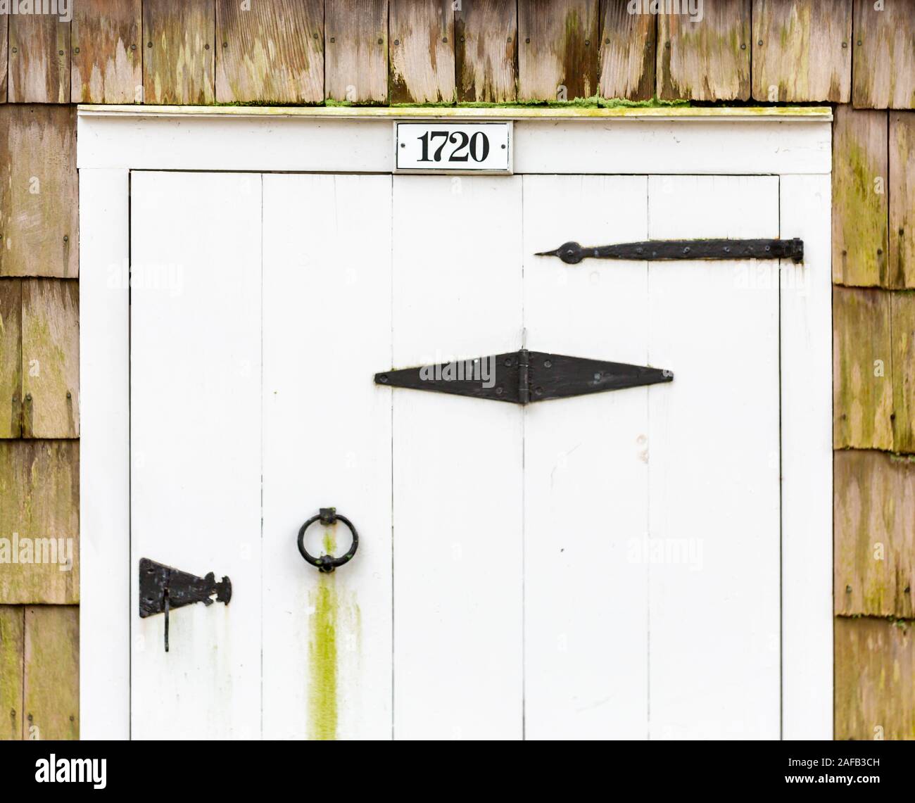 Alte hölzerne weiße Tür mit schwarzen strape Scharniere Stockfoto