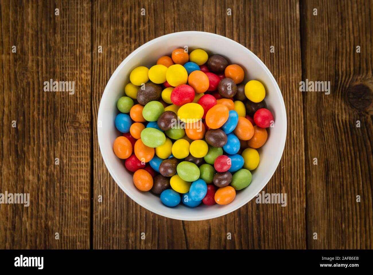 Cocolate beschichtet Erdnüsse auf rustikalen Holzmöbeln Hintergrund (Nahaufnahme) Stockfoto