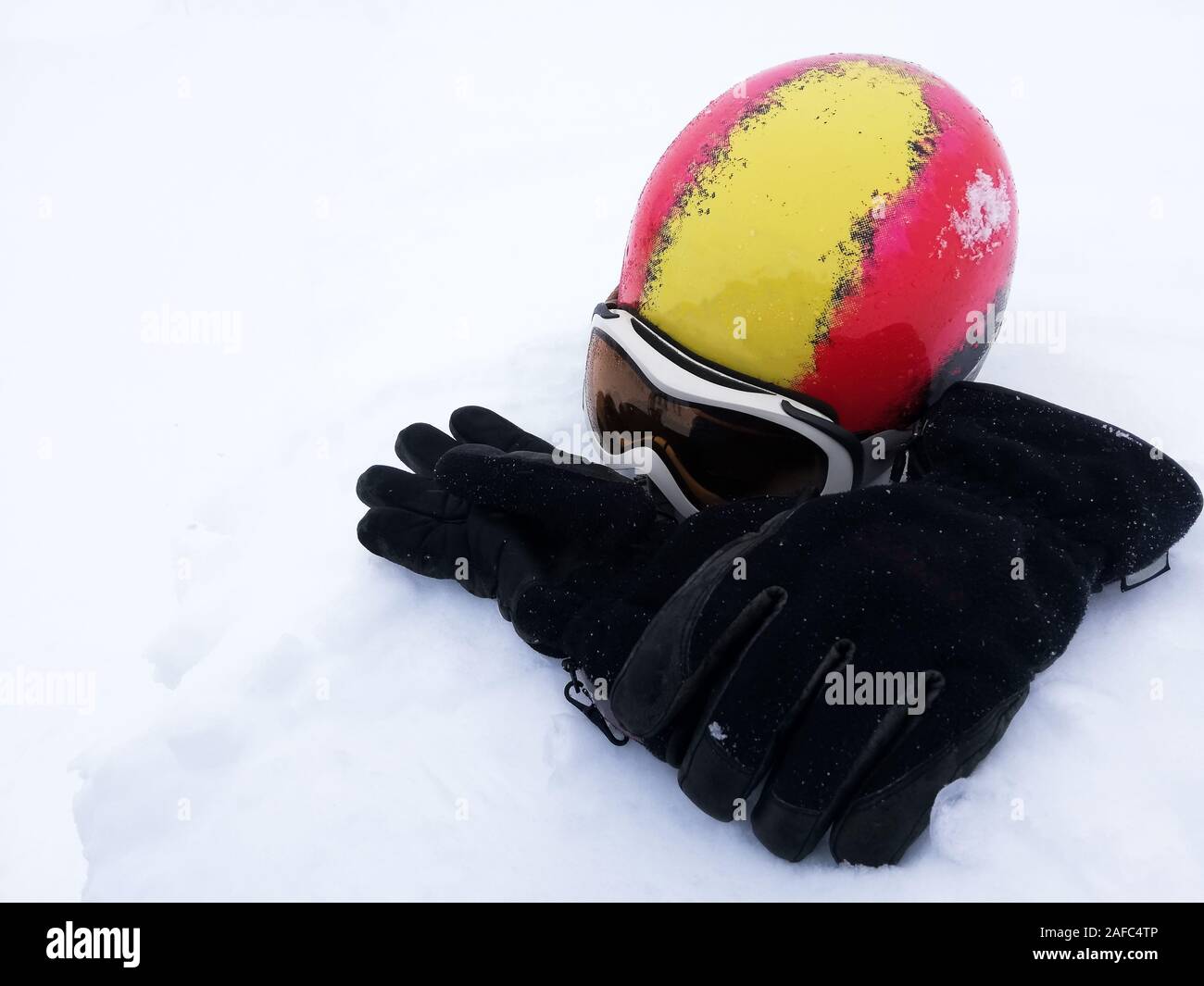 Rote und gelbe Ski Helm, weiße und schwarze Skibrille ski Handschuhe auf Schnee. Winter skifahren Thema Stockfoto