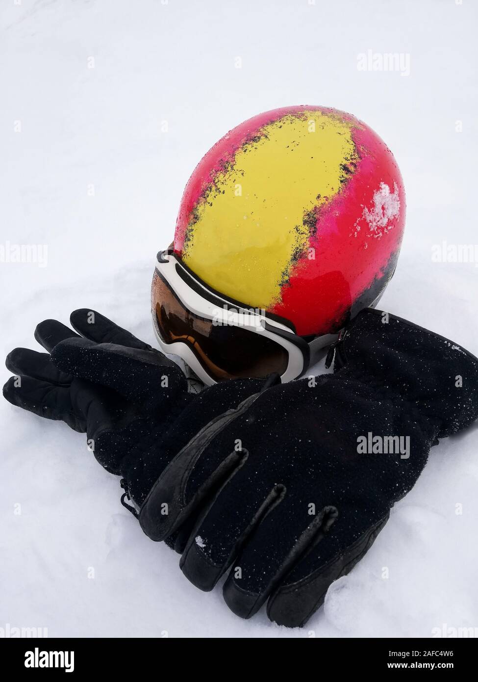 Rote und gelbe Ski Helm, weiße und schwarze Skibrille ski Handschuhe auf Schnee. Winter skifahren Thema Stockfoto