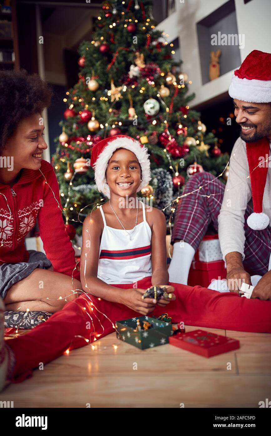 Glückliches Mädchen mit Eltern vor geschmückten Weihnachtsbaum Stockfoto