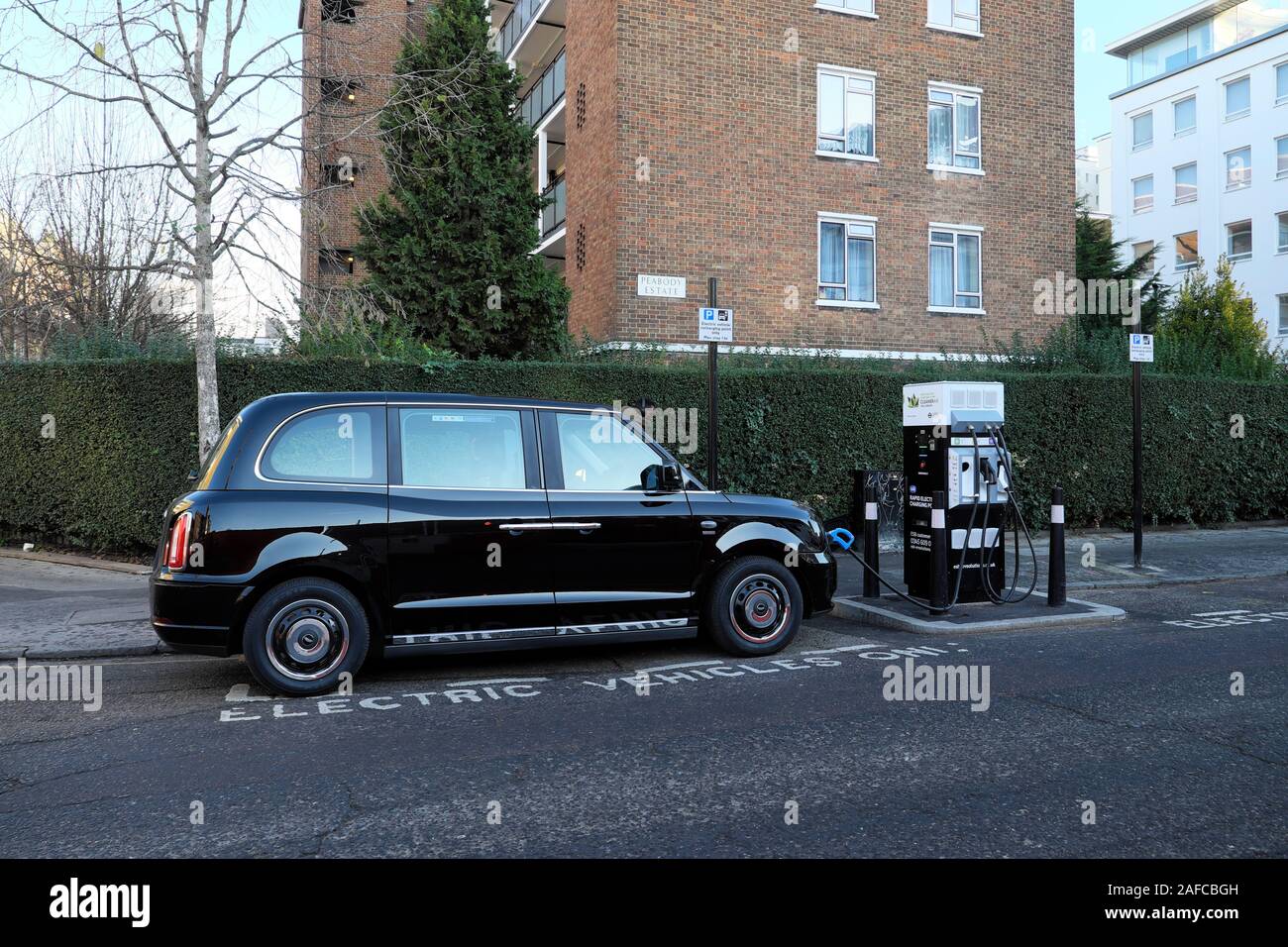 Schwarze Taxi durch eine Ladestation Betankung mit Strom in eine Straße in der City von London England UK KATHY DEWITT geparkt Stockfoto