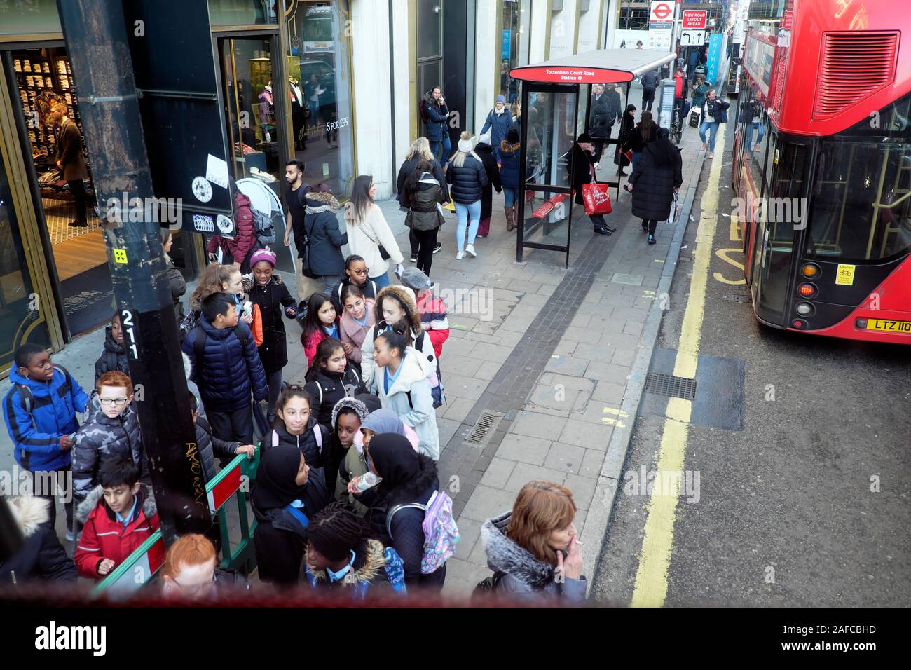 Gruppe von Schulkindern, die auf einen Bus bei einem Besuch der Oxford Street in London, England, Großbritannien, warten, KATHY DEWITT Stockfoto