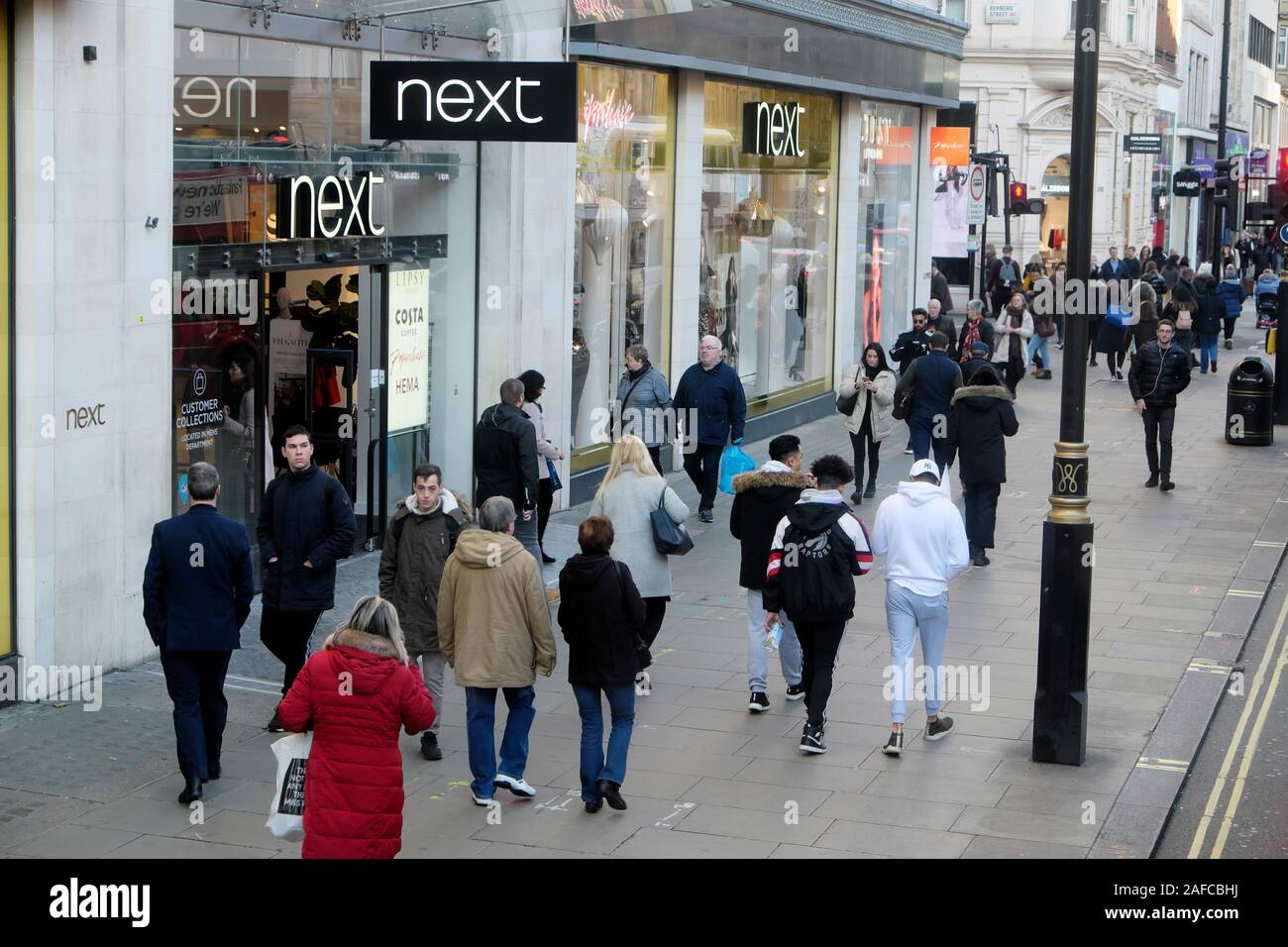 Leute der Käufer vorbei Eingang zum nächsten Store Shopping in der Oxford Street im Winter Dezember London England UK KATHY DEWITT Stockfoto