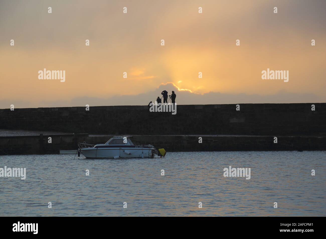 Silhouetten der Fotografen stehen auf dem Cobb in Lyme Regis in der Morgendämmerung Stockfoto