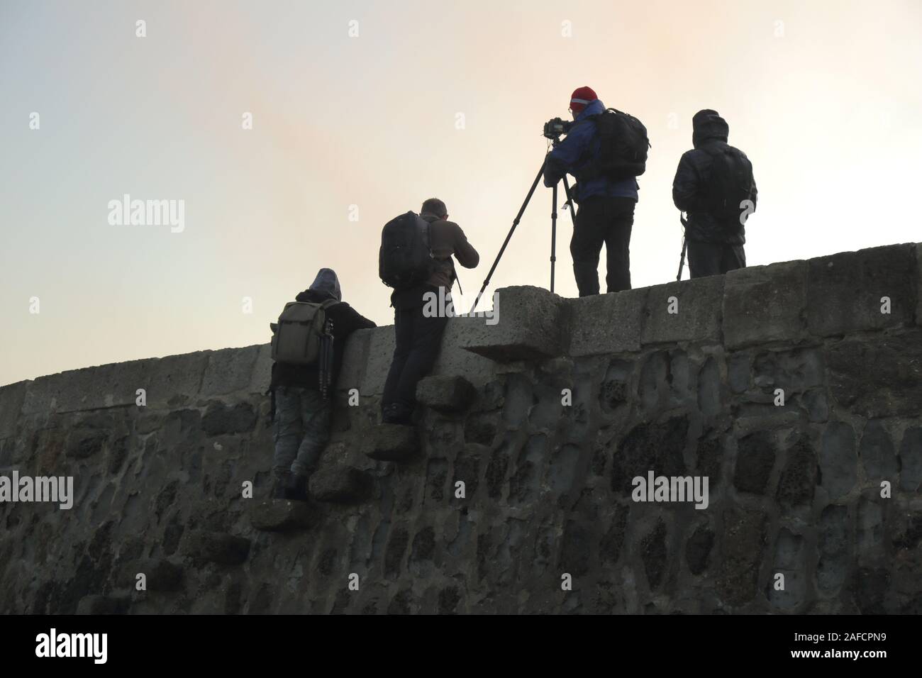 Silhouetten der Fotografen stehen auf dem Cobb in Lyme Regis in der Morgendämmerung Stockfoto