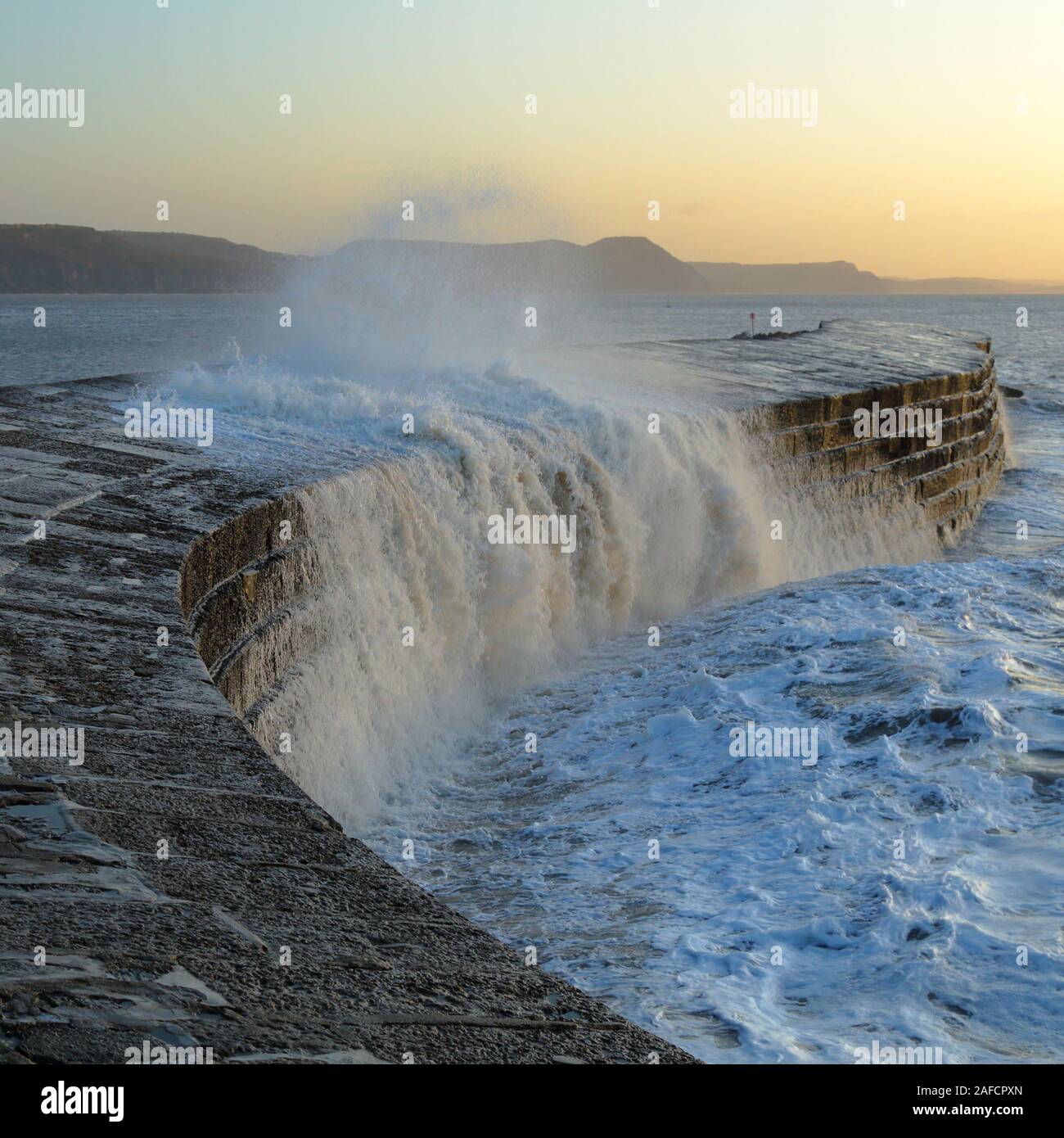 Große Wellen Spritzen auf dem Cobb in Lyme Regis, Dorset durch böigen Winde bei Flut verursacht Stockfoto