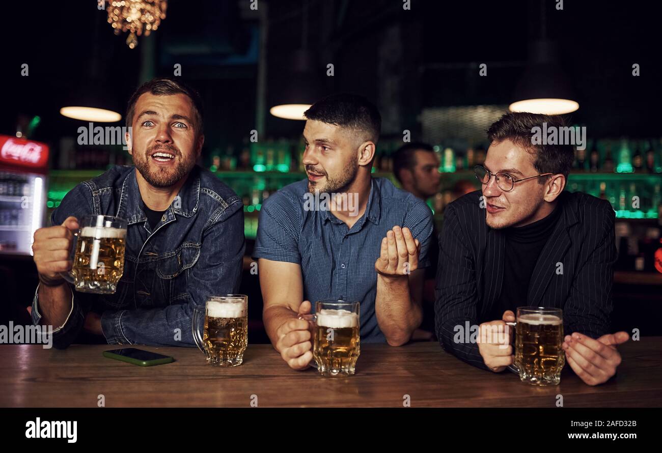 Spaß haben. Freunde in der Kneipe mit Alkohol ruht in den Händen Stockfoto
