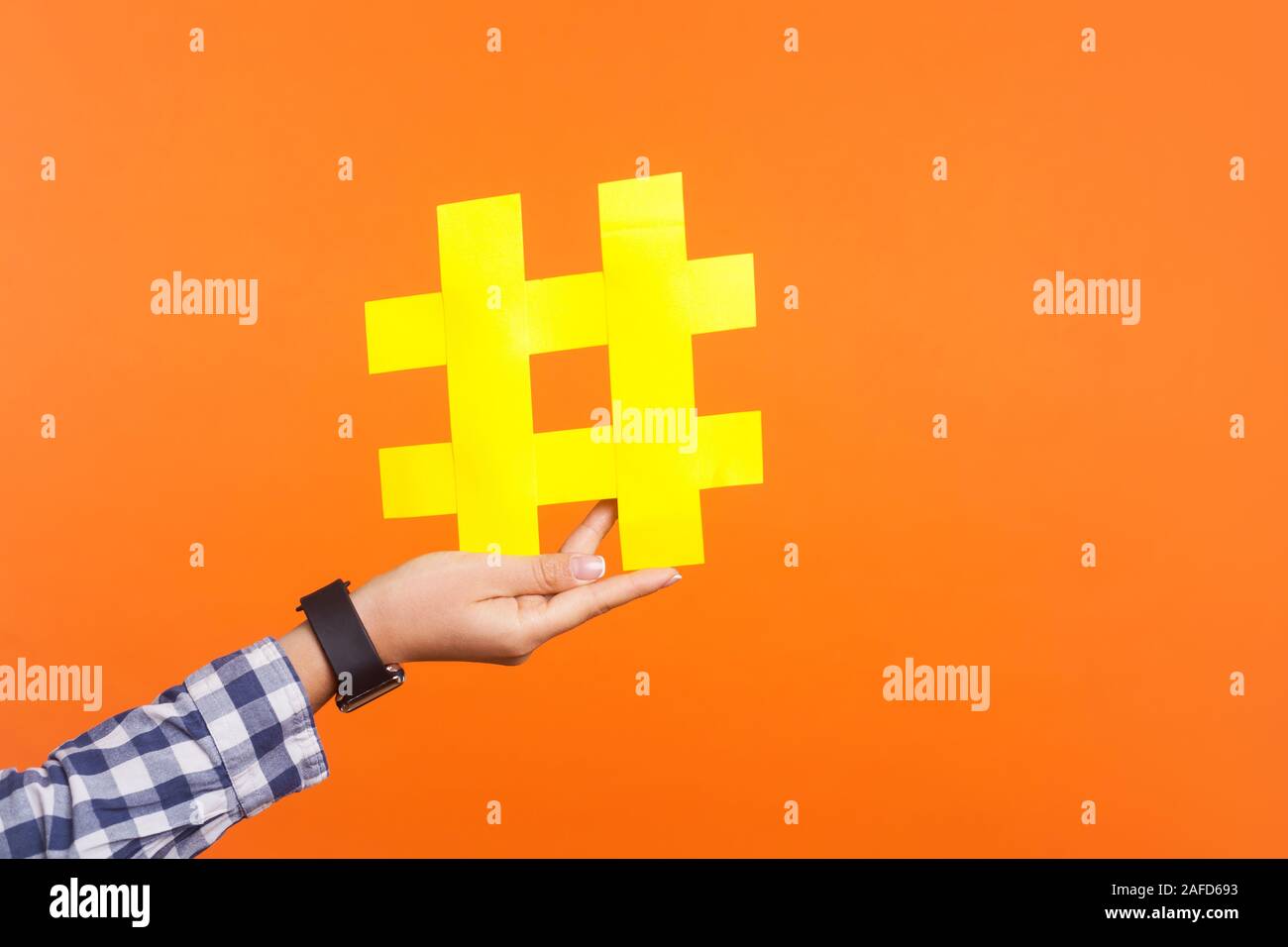 Nahaufnahme der weiblichen Hand große große gelbe hashtag Zeichen, Konzept der trendigen social media Beiträge und Blogs, virale Web Content, Internet Promotion Stockfoto