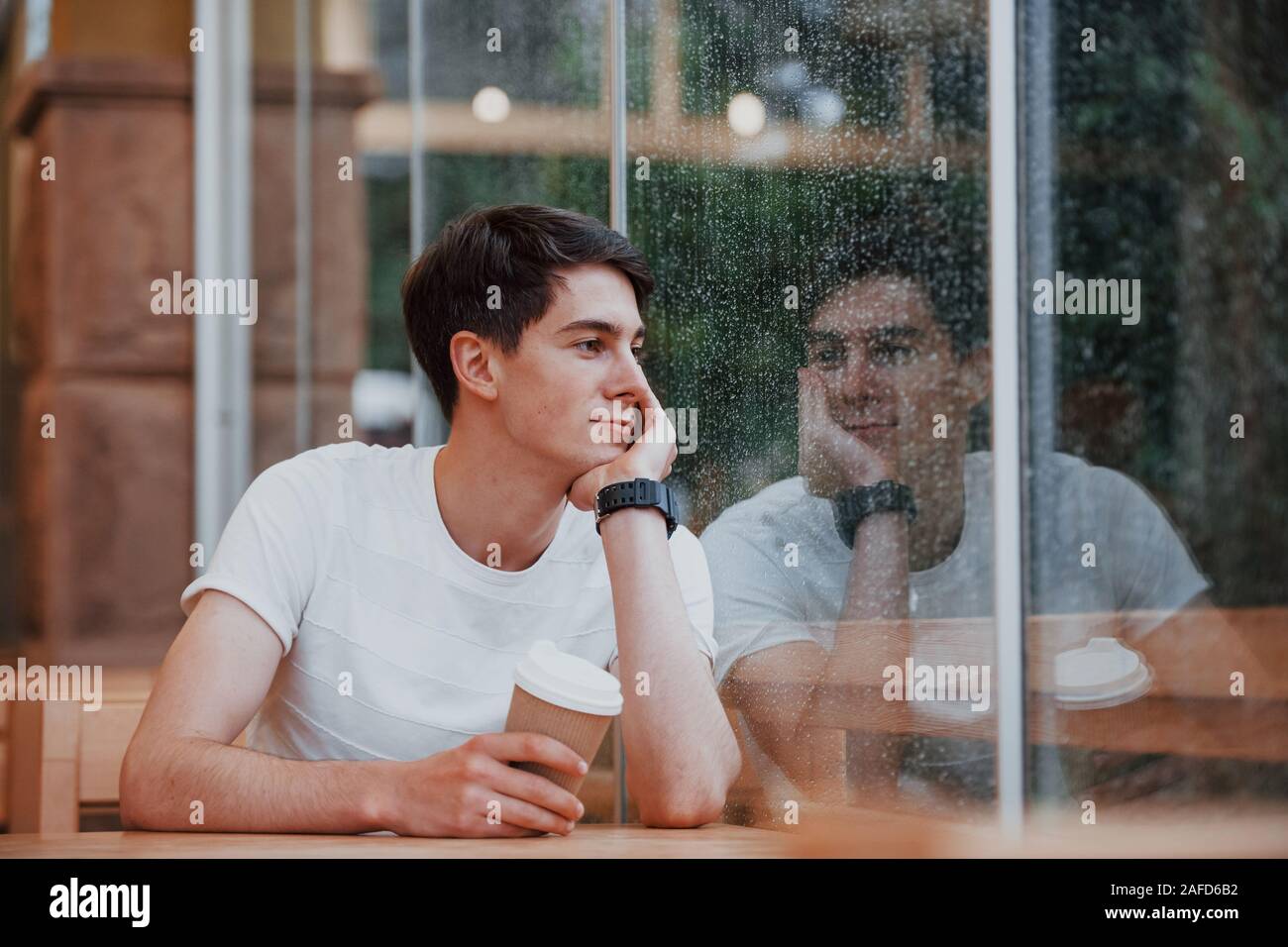 Portrait von jungen Studenten, die im Café zu regnerischen Tag sitzt. Eine Person Stockfoto