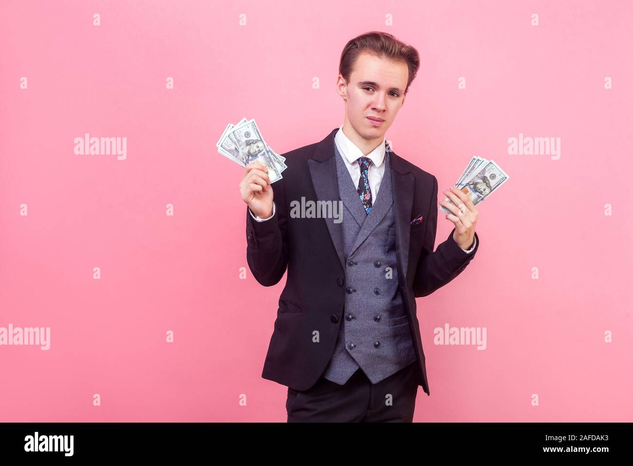 Geld verdienen. Porträt der reiche Geschäftsmann im eleganten Anzug und mit stilvollen Haarschnitt holding Bündeln von Dollar, arrogant und zufrieden mit weal Stockfoto