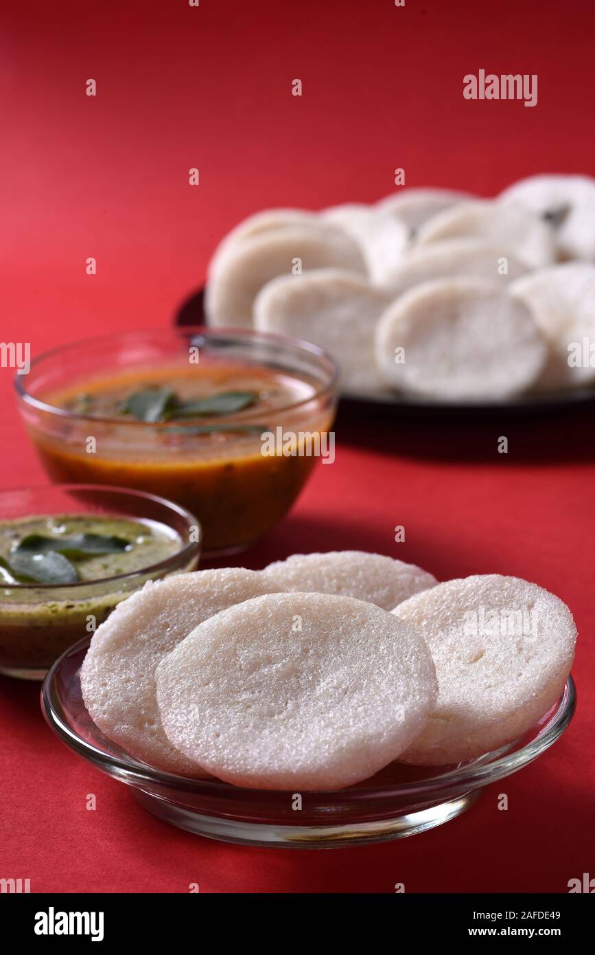 Idli mit Sambar und Kokos Chutney auf rotem Hintergrund, indische ...