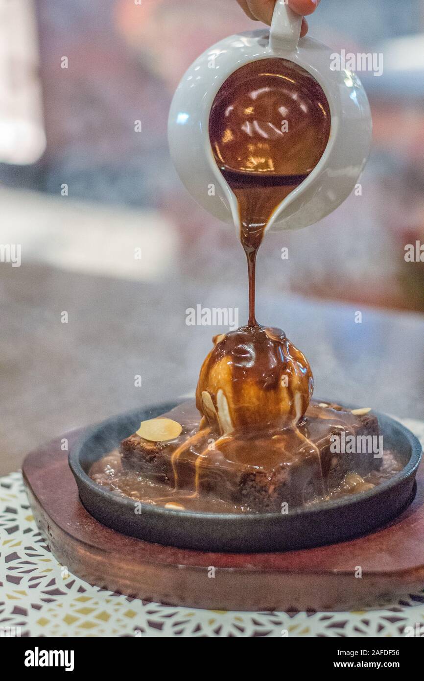 Hot Chocolate Brownie auf sizzling hot plate mit Vanilleeis und gekrönt mit mandelflocken und heißer Schokoladensauce Stockfoto