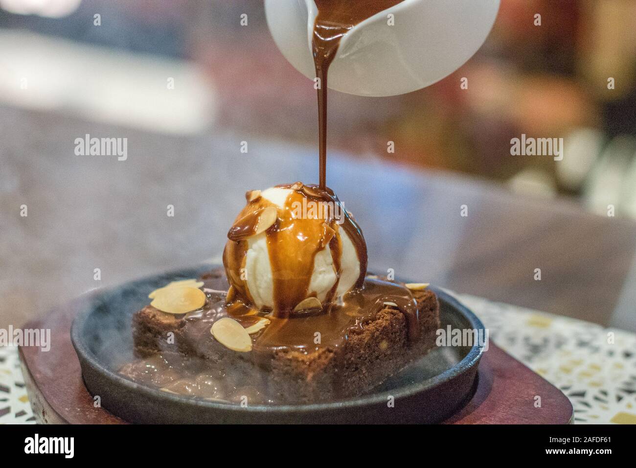 Hot Chocolate Brownie auf sizzling hot plate mit Vanilleeis und gekrönt mit mandelflocken und heißer Schokoladensauce Stockfoto