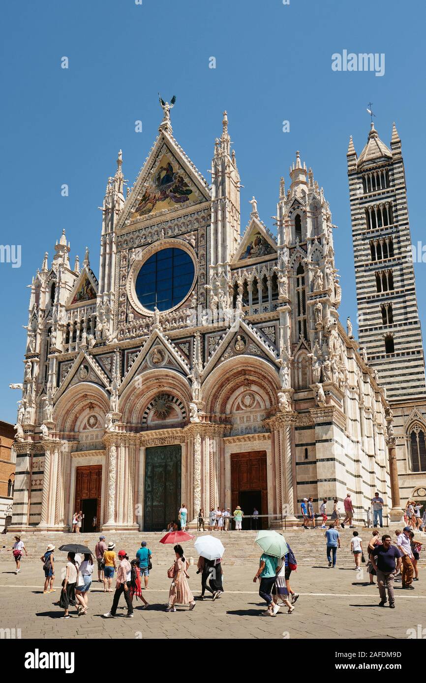 Touristen, die in der Grand mittelalterlichen Westfassade der Kathedrale von Siena/Dom in das UNESCO-Weltkulturerbe von Siena, Toskana, Italien EU Stockfoto