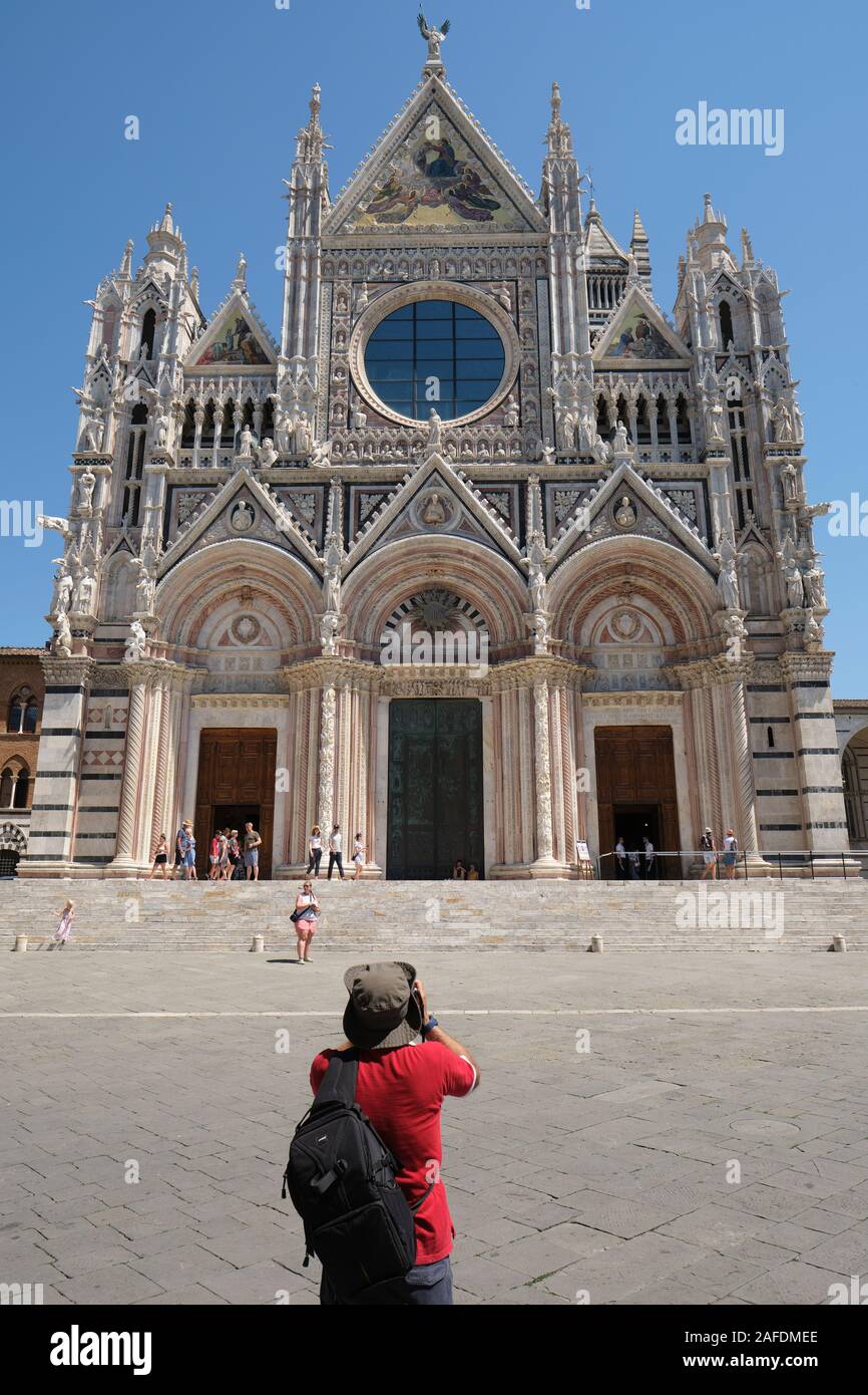 Touristen fotografieren der großen mittelalterlichen Westfassade der Kathedrale von Siena/Dom in das UNESCO-Weltkulturerbe von Siena, Toskana, Italien EU Stockfoto