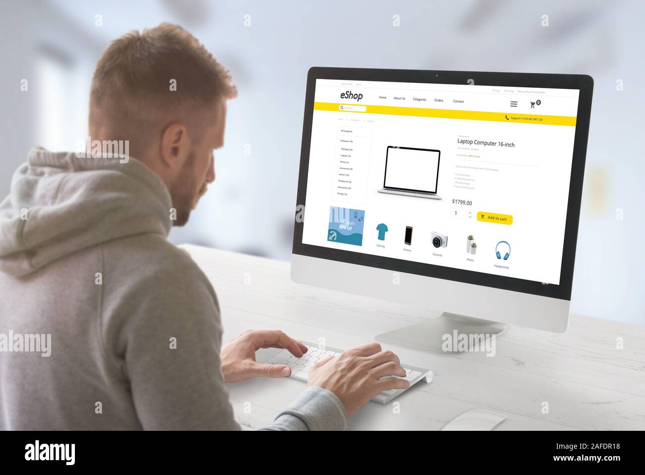 Guy shopping online auf dem Desktop Computer. Moderne online Markt Website mit Technologie Produkte und Banner auf der Anzeige Stockfoto