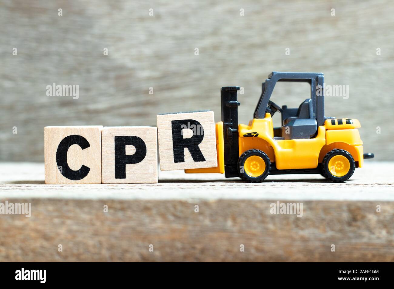 Spielzeug Gabelstapler halten schreiben Block R zu Wort (Abkürzung der kardiopulmonalen Reanimation) auf Holz Hintergrund abgeschlossen Stockfoto