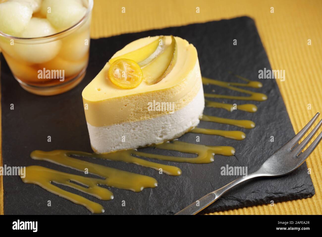 Mango und Sauerrahm Dessert gekrönt mit Schichten von Mango auf einer Schiefertafel Anlage mit Melone Punch Stockfoto