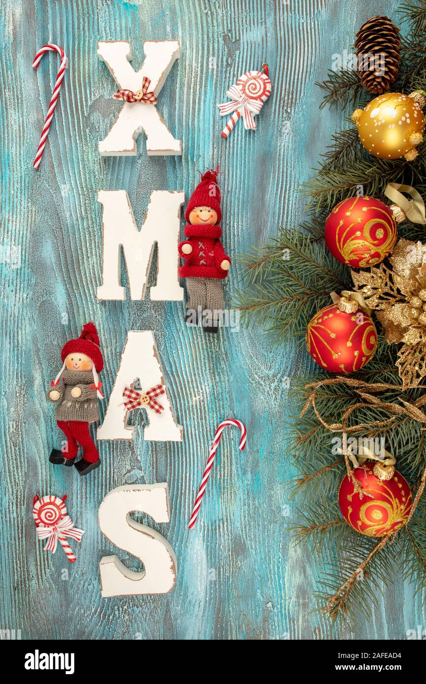 Weihnachten Hintergrund. Tannenbaum Äste mit Weihnachten Dekoration und weißen Holzmöbeln Buchstaben bilden Wort XMAS auf blauem Hintergrund. Stockfoto