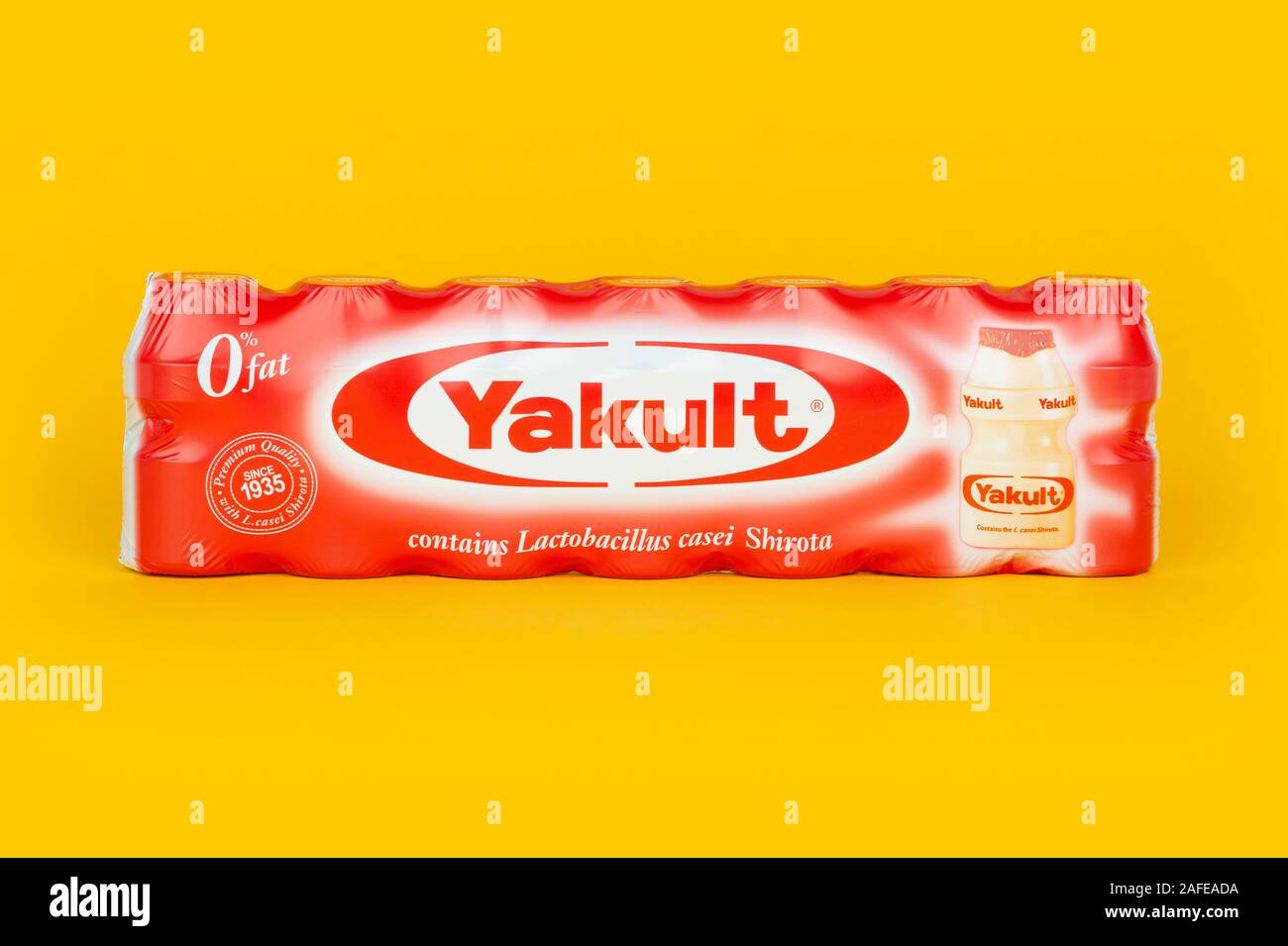 Eine 7er Packung von Yakult gesüßt probiotischen Milch trinken Flaschen Schuß auf einen gelben Hintergrund. Stockfoto