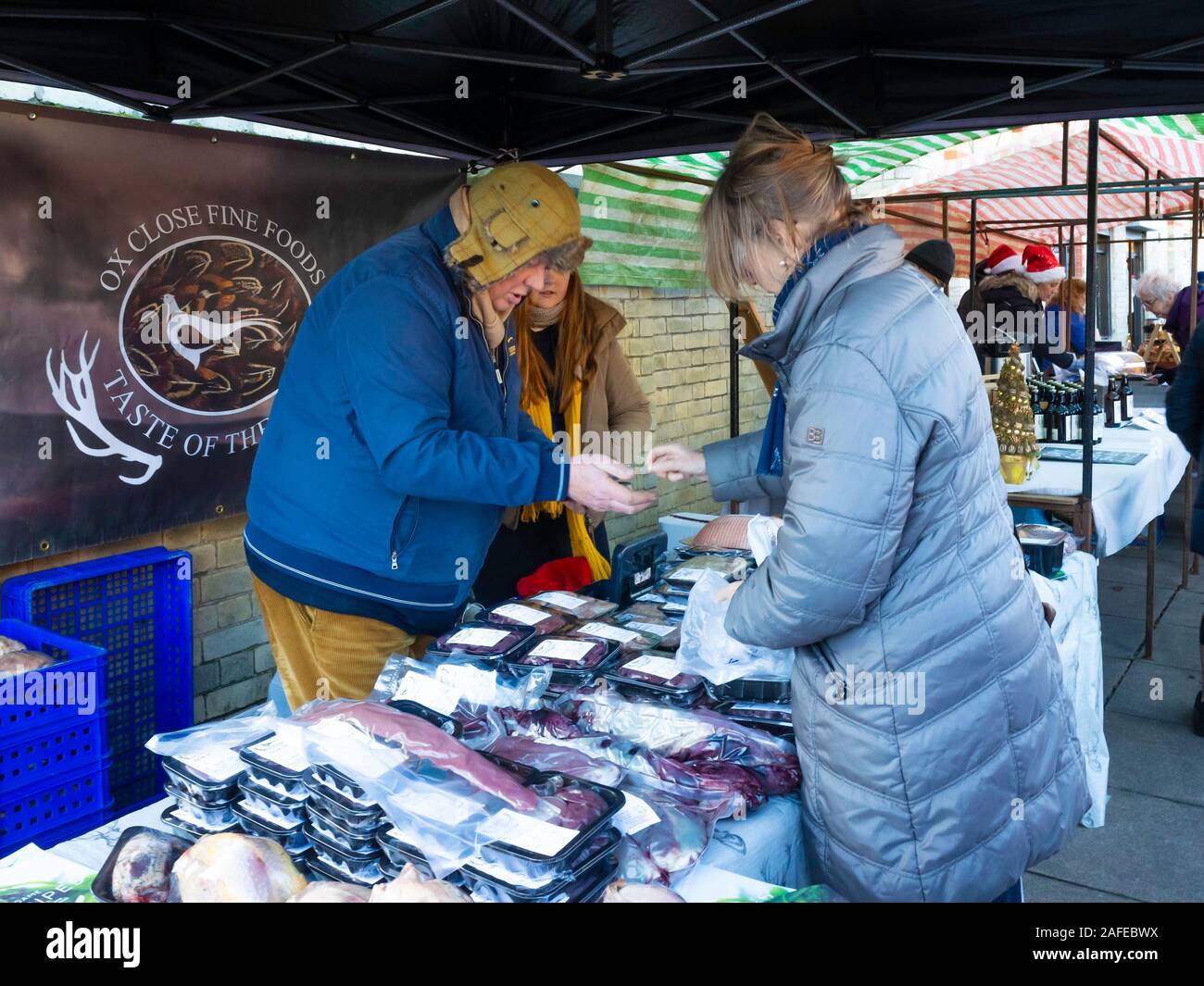 Ein Spezialist der Verkäufer ein Bauernmarkt Verkauf von fasanen zu einem älteren Dame Strebe Stockfoto