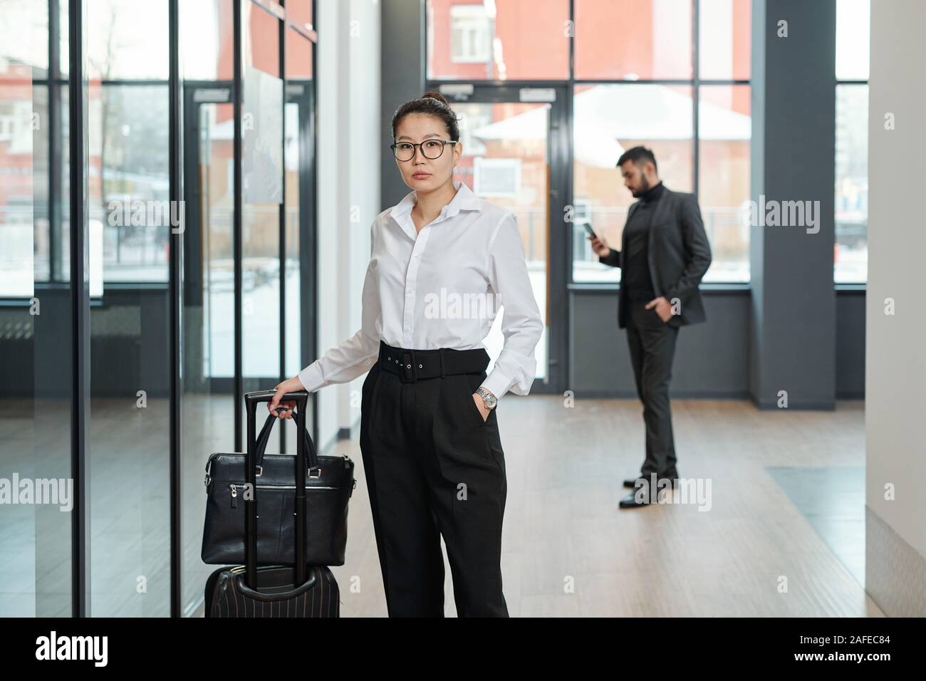 Junge elegante Geschäftsfrau der Asiatischen Ethnie ziehen Koffer im Flughafen Stockfoto
