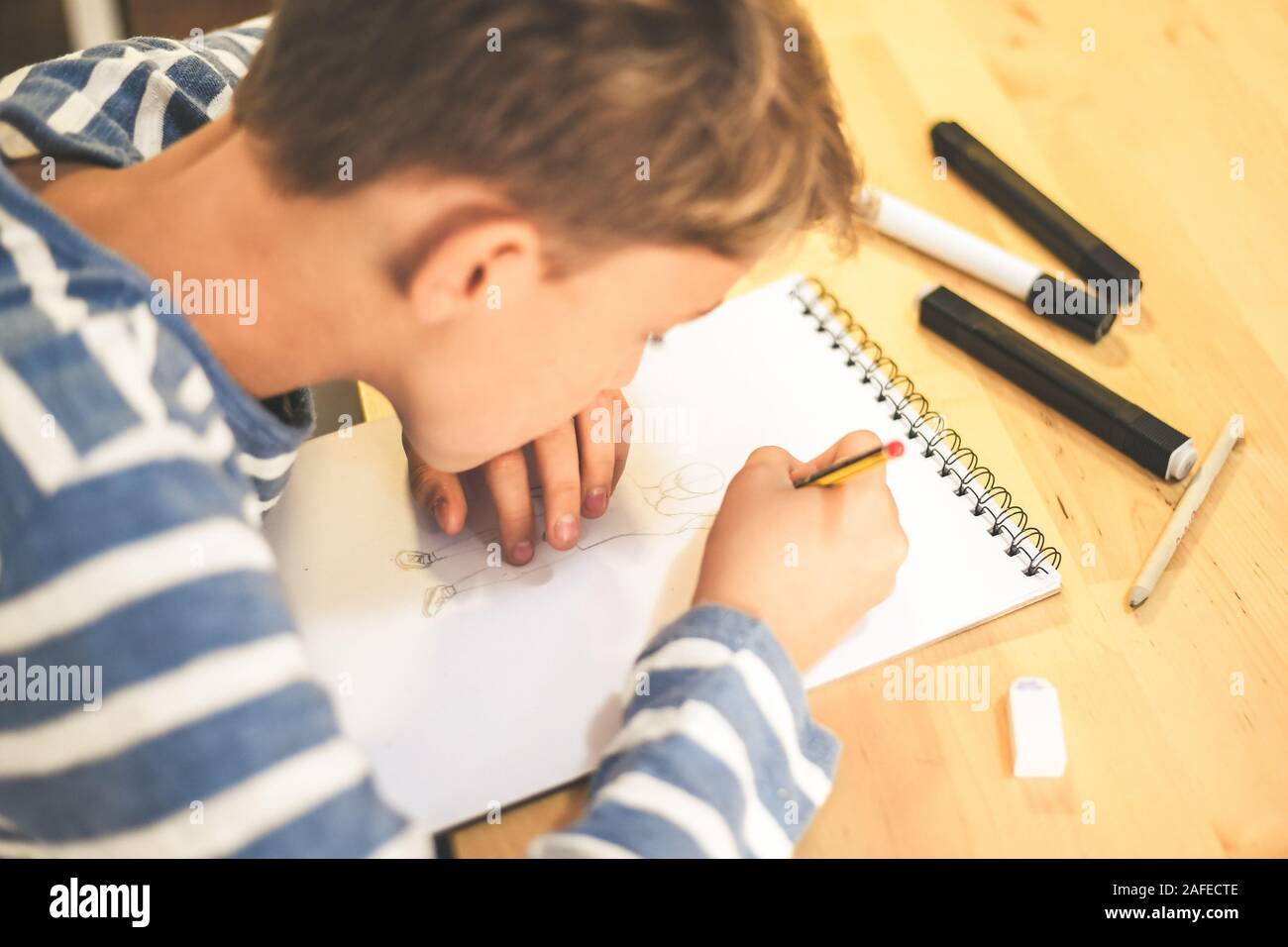 Nahaufnahme der Schüler Zeichnen mit Bleistift. Junge Hausaufgaben schreiben auf ein Papier. Kid halten Sie einen Bleistift und ein Manga zu Hause ziehen. Jugendlich Zeichnung sitzen Stockfoto
