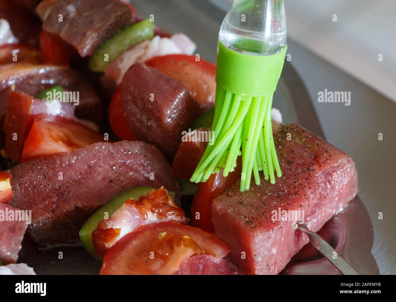 Öl zu setzen mit einem silikon Pinsel auf Rindfleisch brochettes Stockfoto