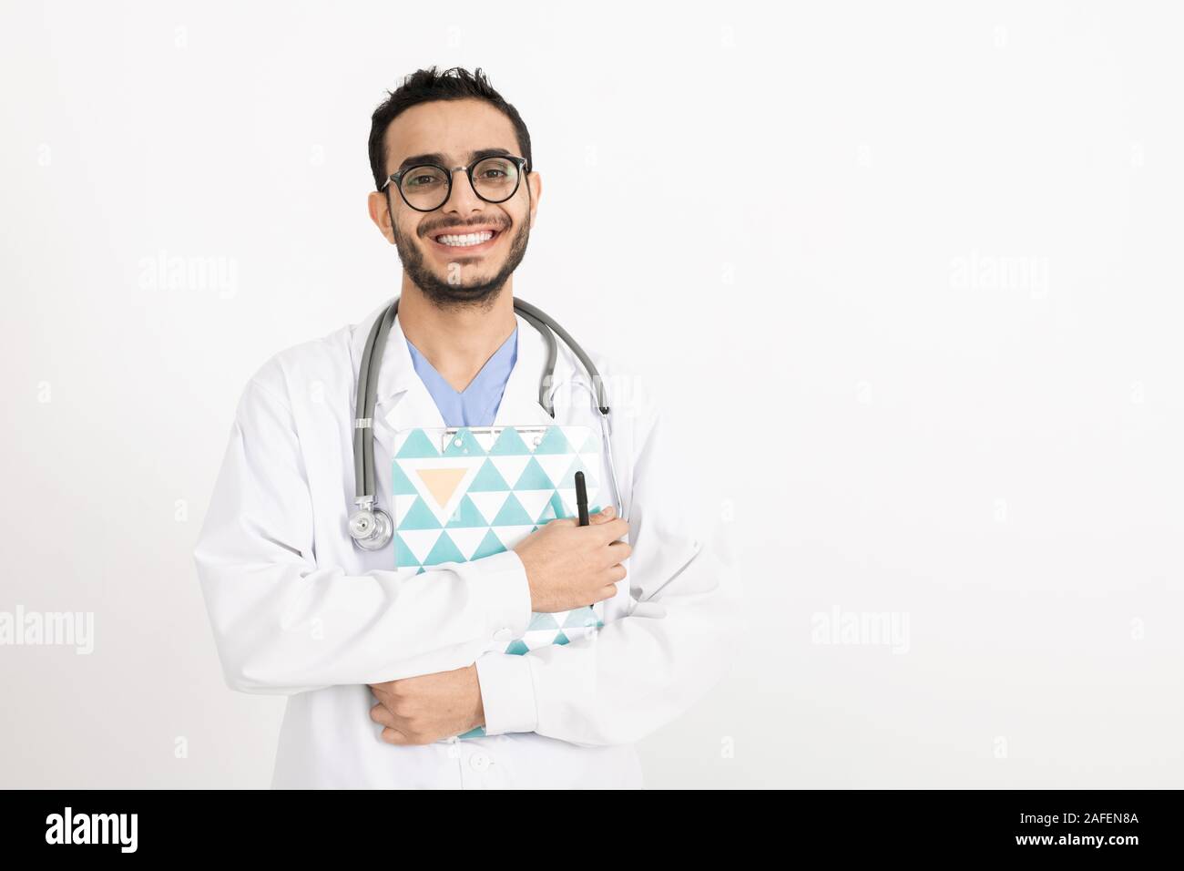 Glückliche junge erfolgreiche Kliniker mit Stethoskop, Zwischenablage und Stift Stockfoto