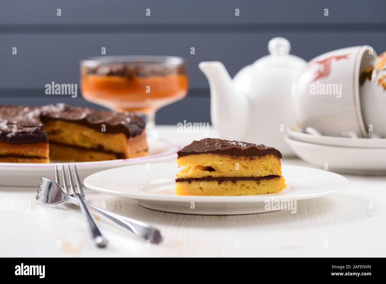 Weißer Fayence Teeutensilien, hausgemachte Desserts und geschichteten callorie Kürbis Kürbis Kuchen mit Schokoladenglasur und Gabeln Stockfoto