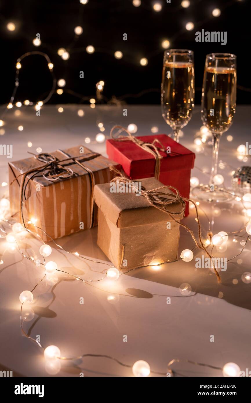 Drei verpackt giftboxes, zwei Flöten der Champagner auf dem Tisch mit Girlanden dekoriert Stockfoto